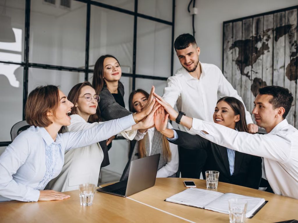 Group sharing a high-five around a meeting table