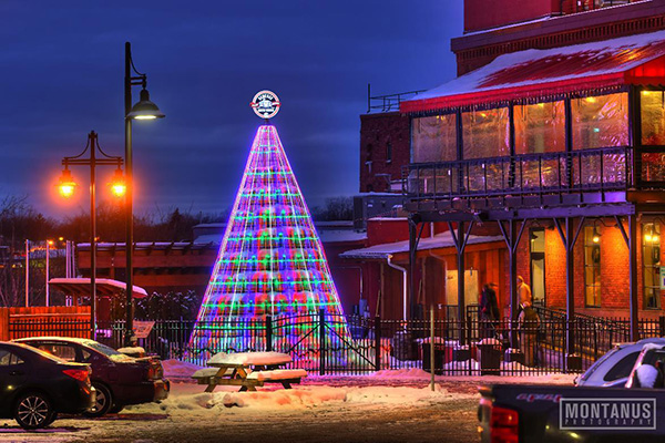 Multicolored Christmas tree lights outside a brick building on a snowy evening