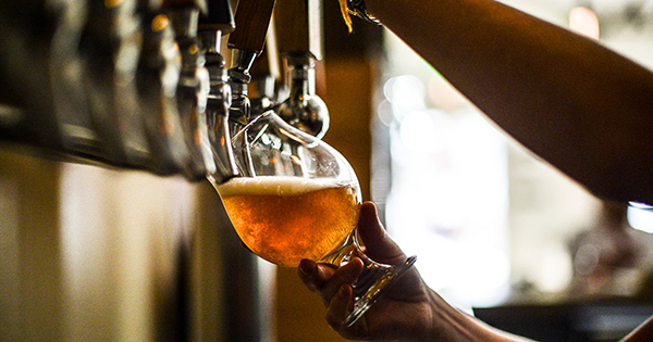 Beer being poured from a tap into a stemmed glass