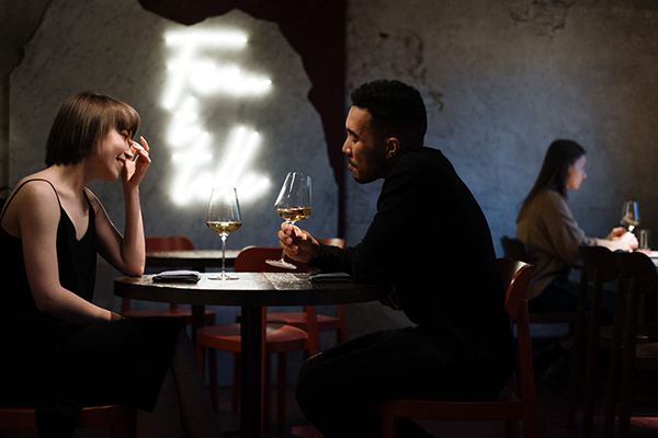 Two people talking over wine at a small café table
