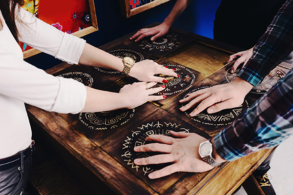 Players working together on circular symbol puzzles set into a wooden table.