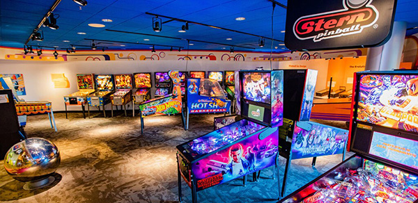 Rows of colorful pinball machines beneath a Stern Pinball sign