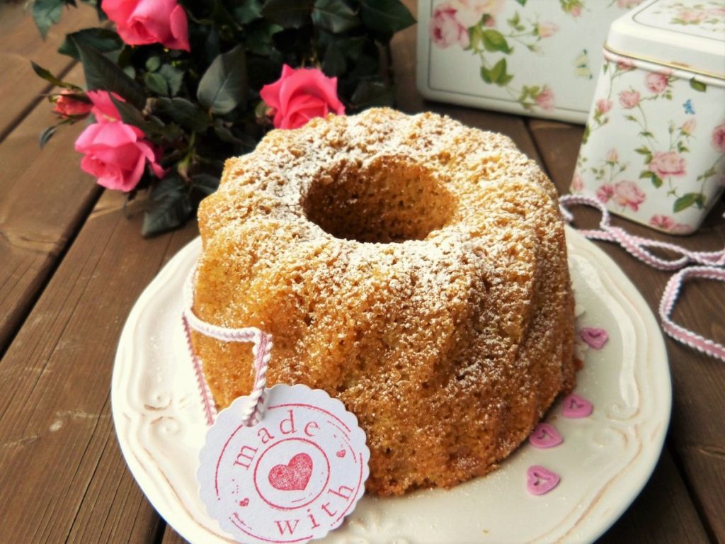 Sugar-dusted ring cake on a plate with heart decorations and a gift tag