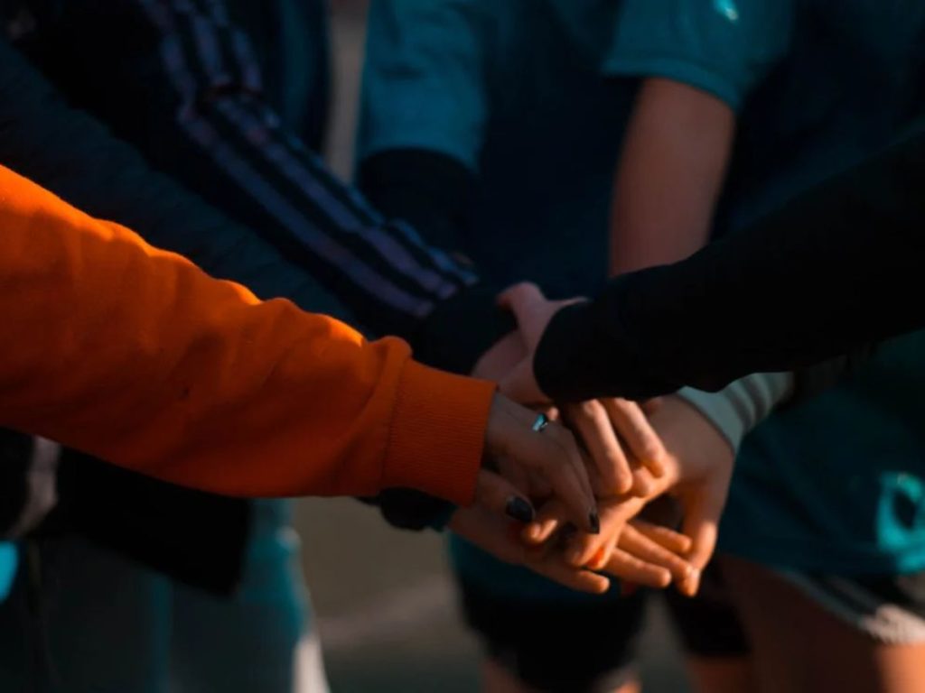 Group members stacking their hands together in a team huddle.