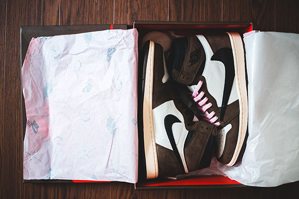 Brown-and-white high-top sneakers with pink laces in an open shoebox