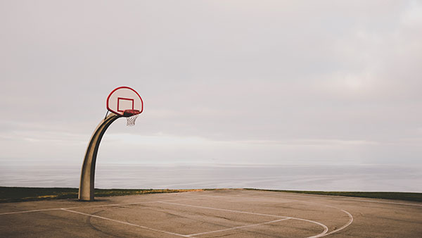 Empty outdoor basketball court with a single hoop