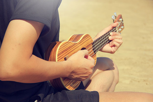 Person playing a striped wooden ukulele