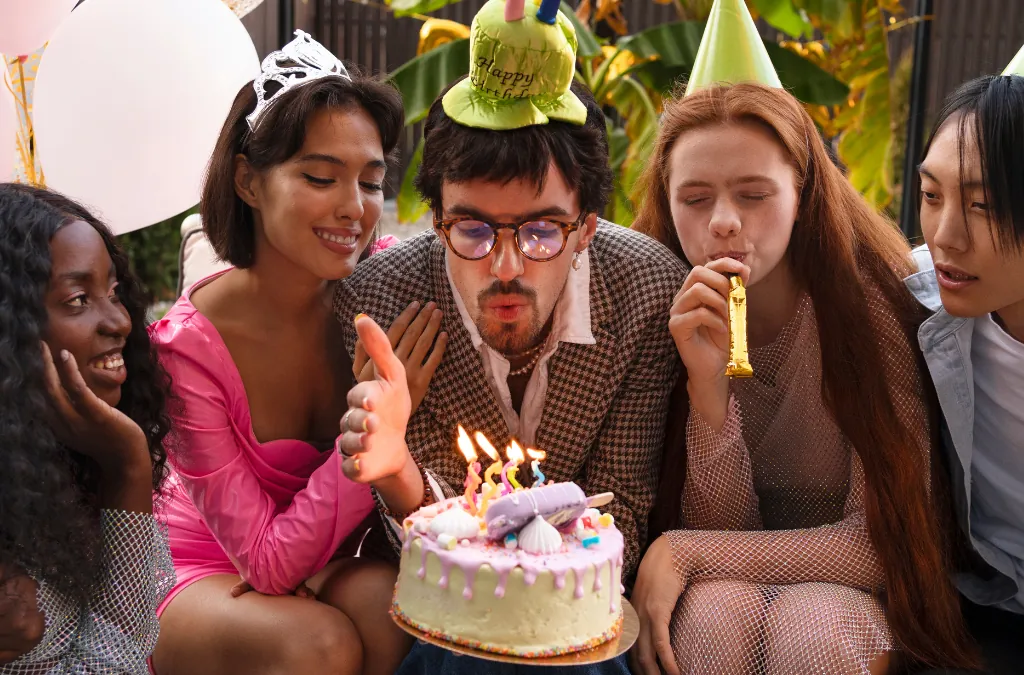 Group of friends celebrating a birthday with cake and party hats