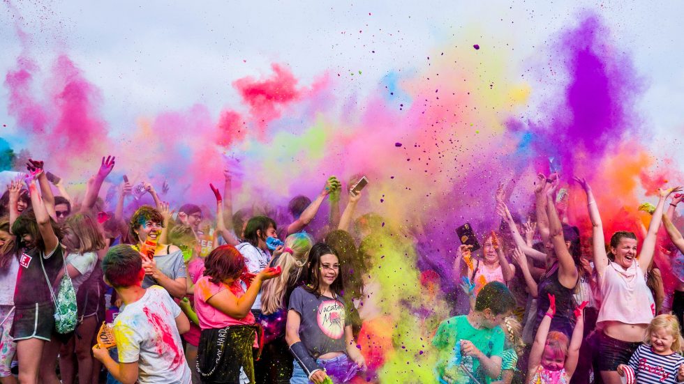 Crowd celebrating with colorful powder in the air at an outdoor event