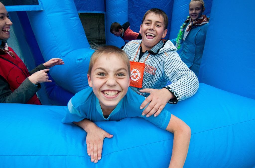 Two kids smiling inside a blue inflatable bounce house at an event