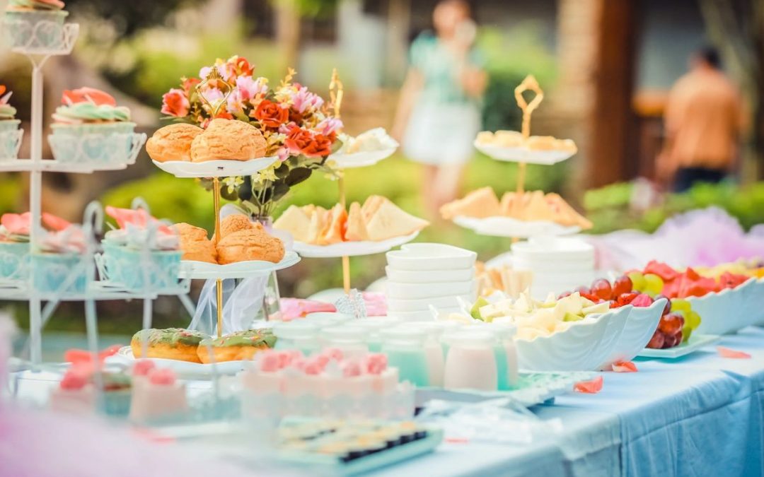 Colorful dessert and snack buffet table with pastries, fruit, and flowers