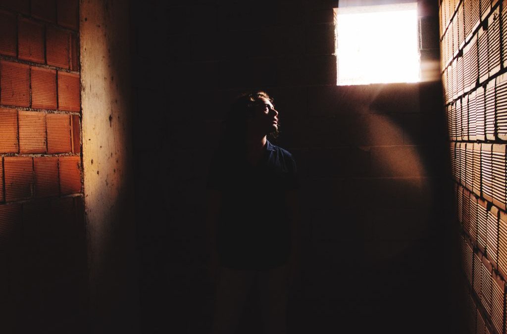 Person standing in dark hallway with light streaming through window