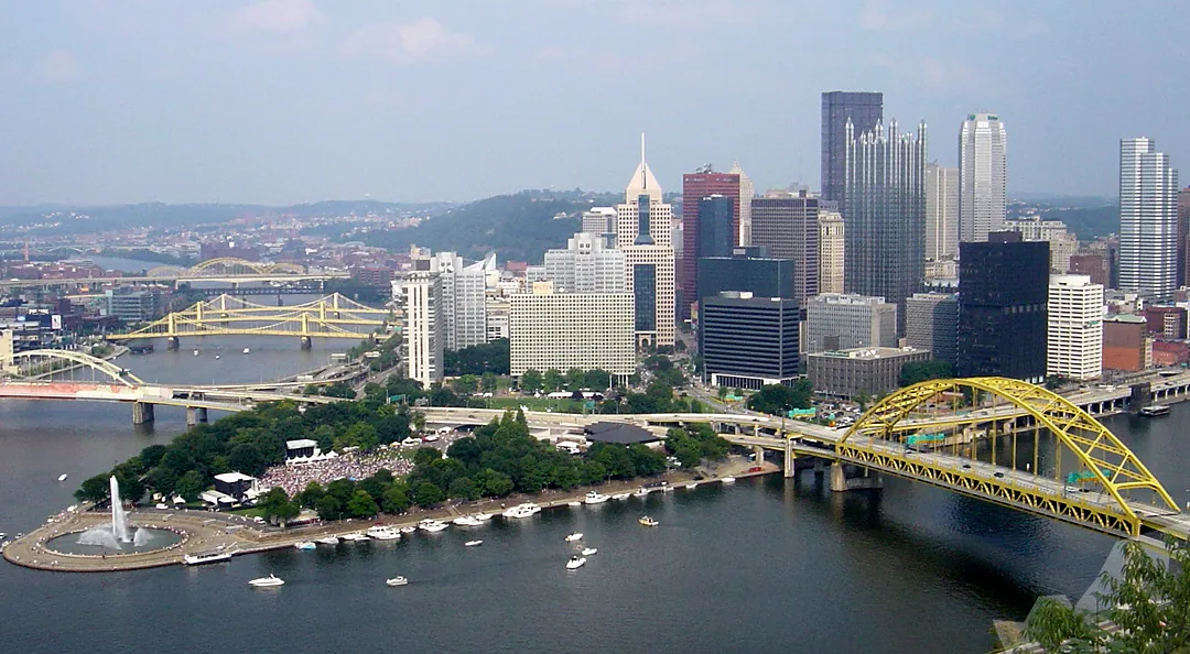 Pittsburgh city skyline with yellow bridge over river and fountain