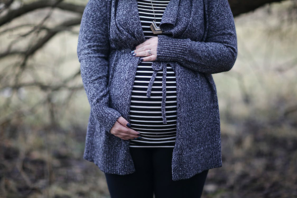 Pregnant woman in striped shirt and cardigan outdoors