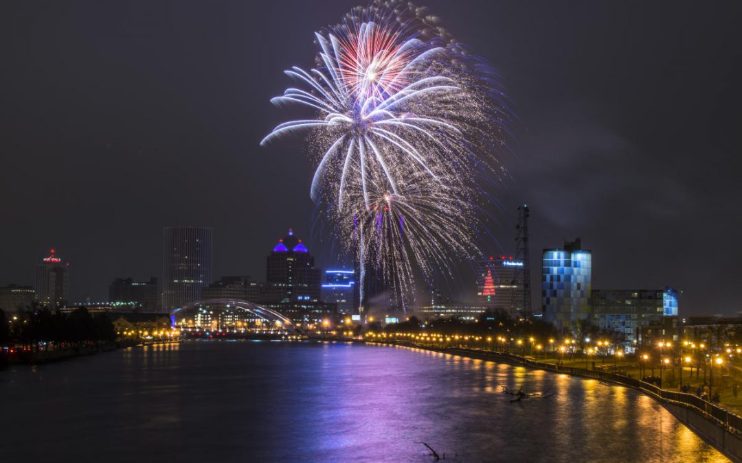 Fireworks display over Rochester city skyline at night with river in foreground
