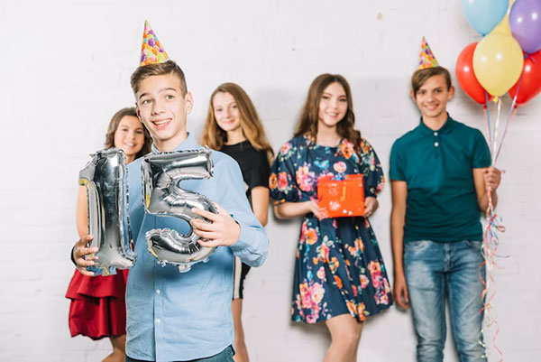 Teenagers celebrating 15th birthday with balloons and party hats